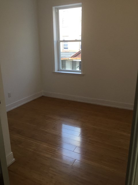an empty room with a window and wooden floors