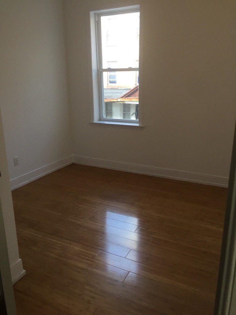 an empty room with a window and wooden floors