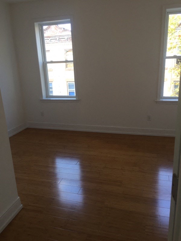 an empty room with a wooden floor and two windows