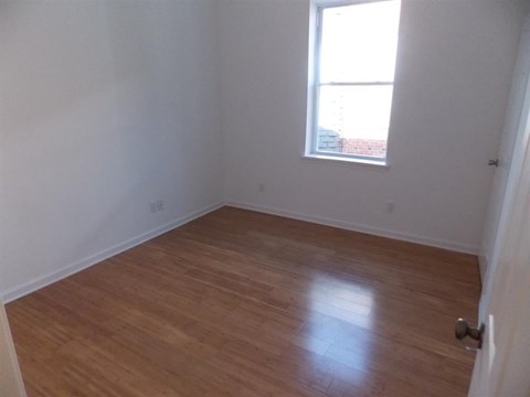 an empty room with a window and wooden floors