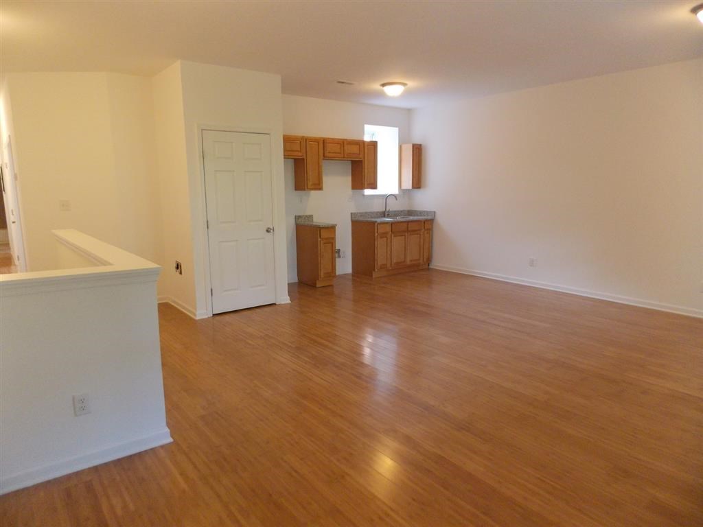 an empty living room and kitchen with a wooden floor