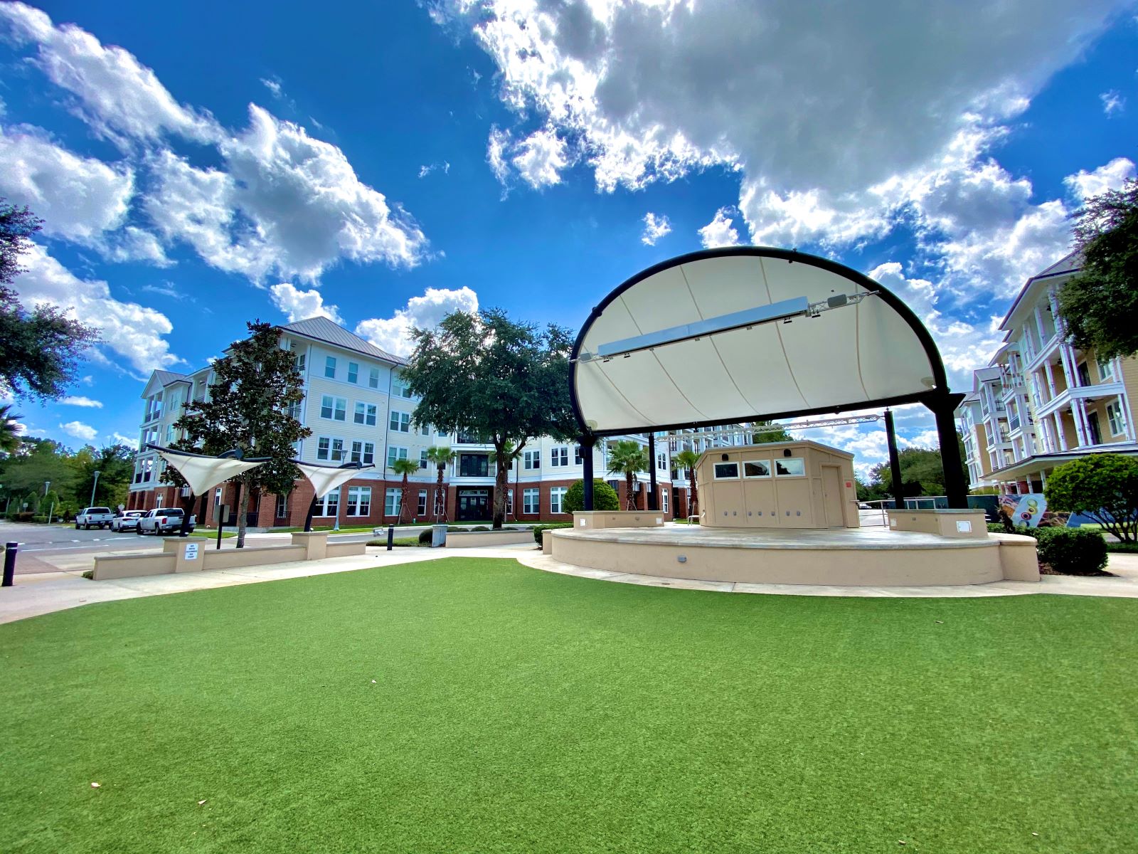 An outdoor stage at the Tioga Town Center with astro turf and trees near The Flats at Tioga Town Center apartments.