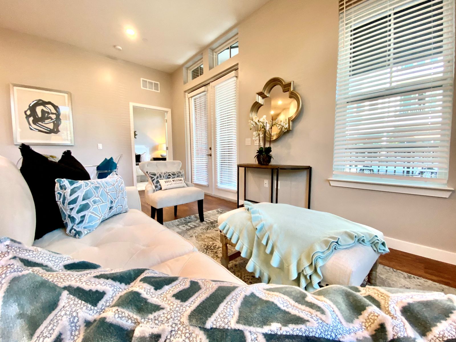 A living room with a window, hardwood-style flooring, and near double doors to a private balcony.