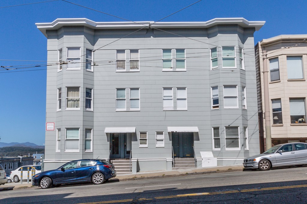 a white apartment building on a city street with cars