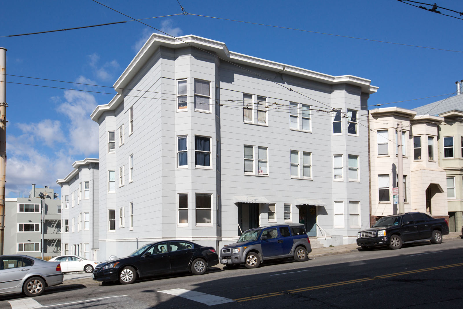 A street view of a building with cars parked in front.
