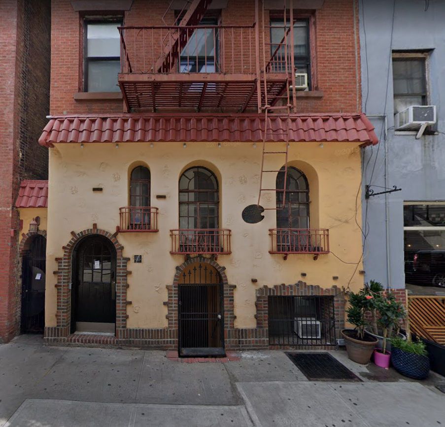 the front of a building with a yellow facade and a balcony