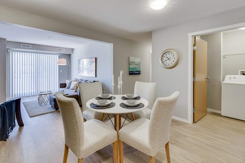 A dining room with a table set for two and a clock on the wall.