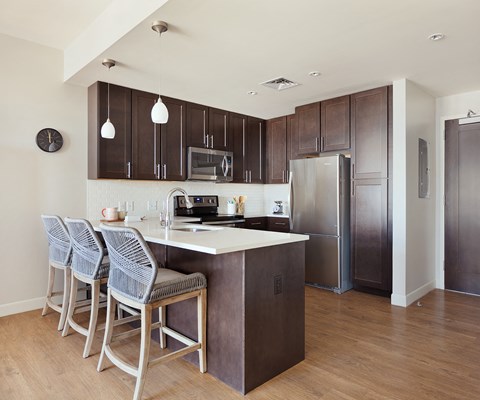 a kitchen with stainless steel appliances and a bar with three stools