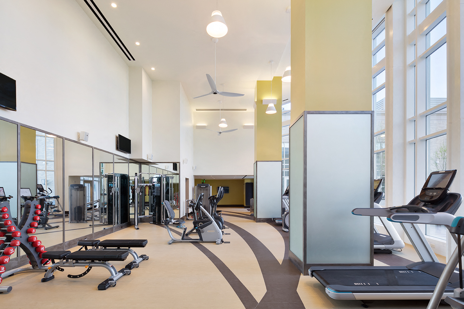 a gym with treadmills and other exercise equipment in a building with large windows