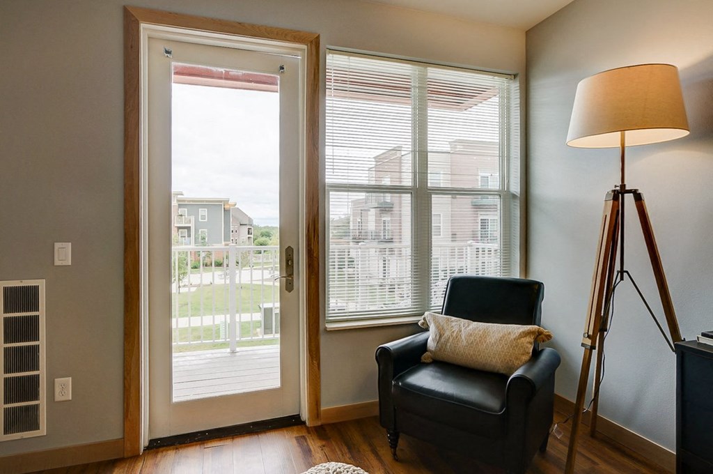 a living room with a black chair and sliding glass doors