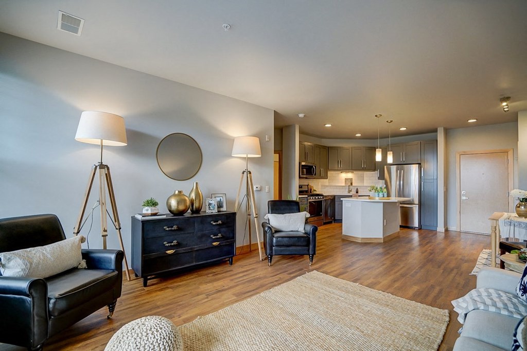 a living room with furniture and a kitchen in the background
