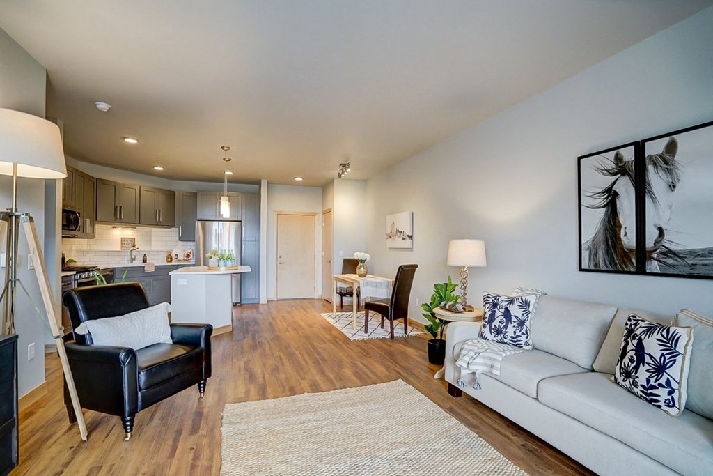 a living room and kitchen with a couch and chairs