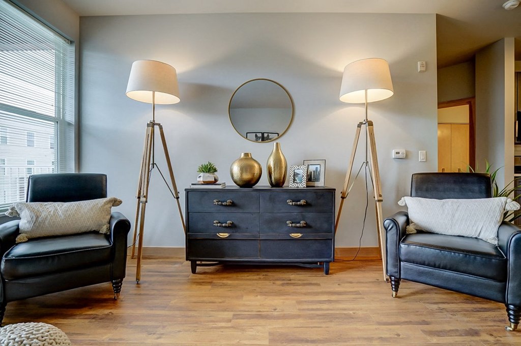 a living room with blue chairs and a mirror and lamps