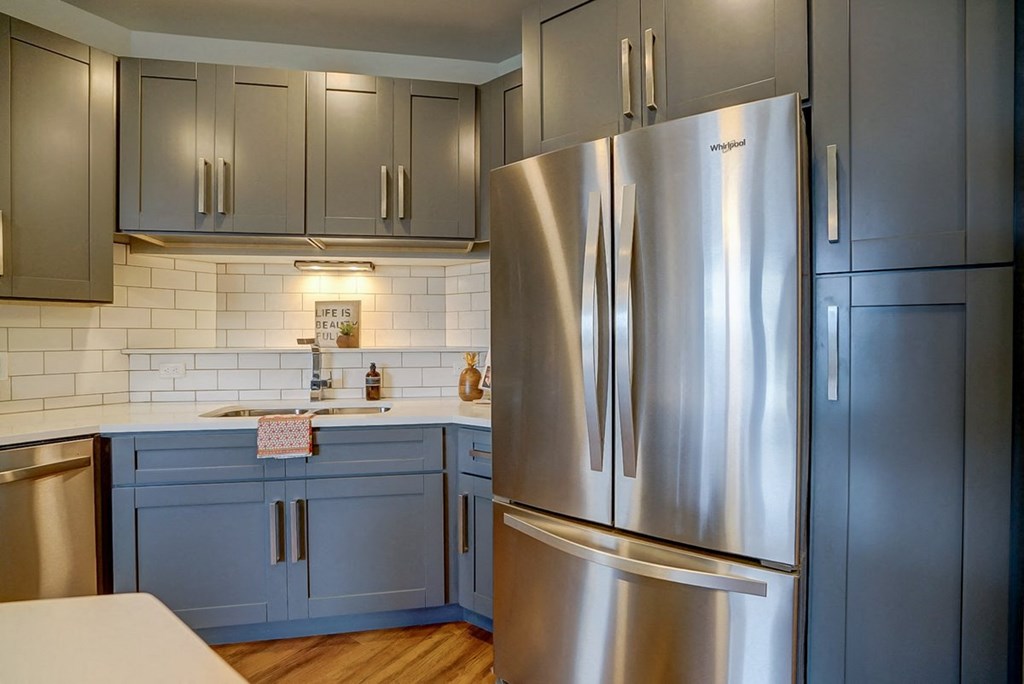 a kitchen with blue cabinets and a stainless steel refrigerator