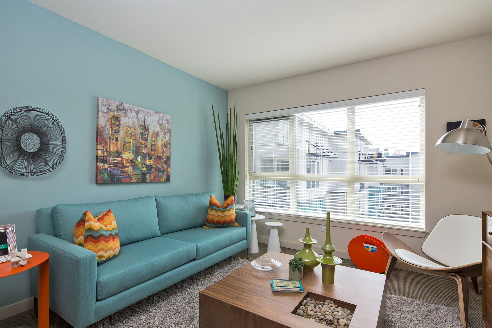 A living room with a blue couch and a painting on the wall.