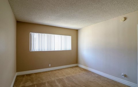 the spacious living room of an empty home with a window
