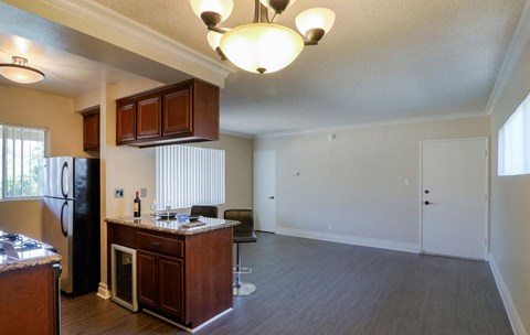 an empty kitchen and living room with a refrigerator and a sink