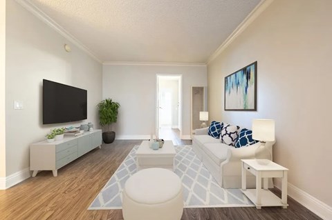 A living room with a white couch and a television on the wall.
