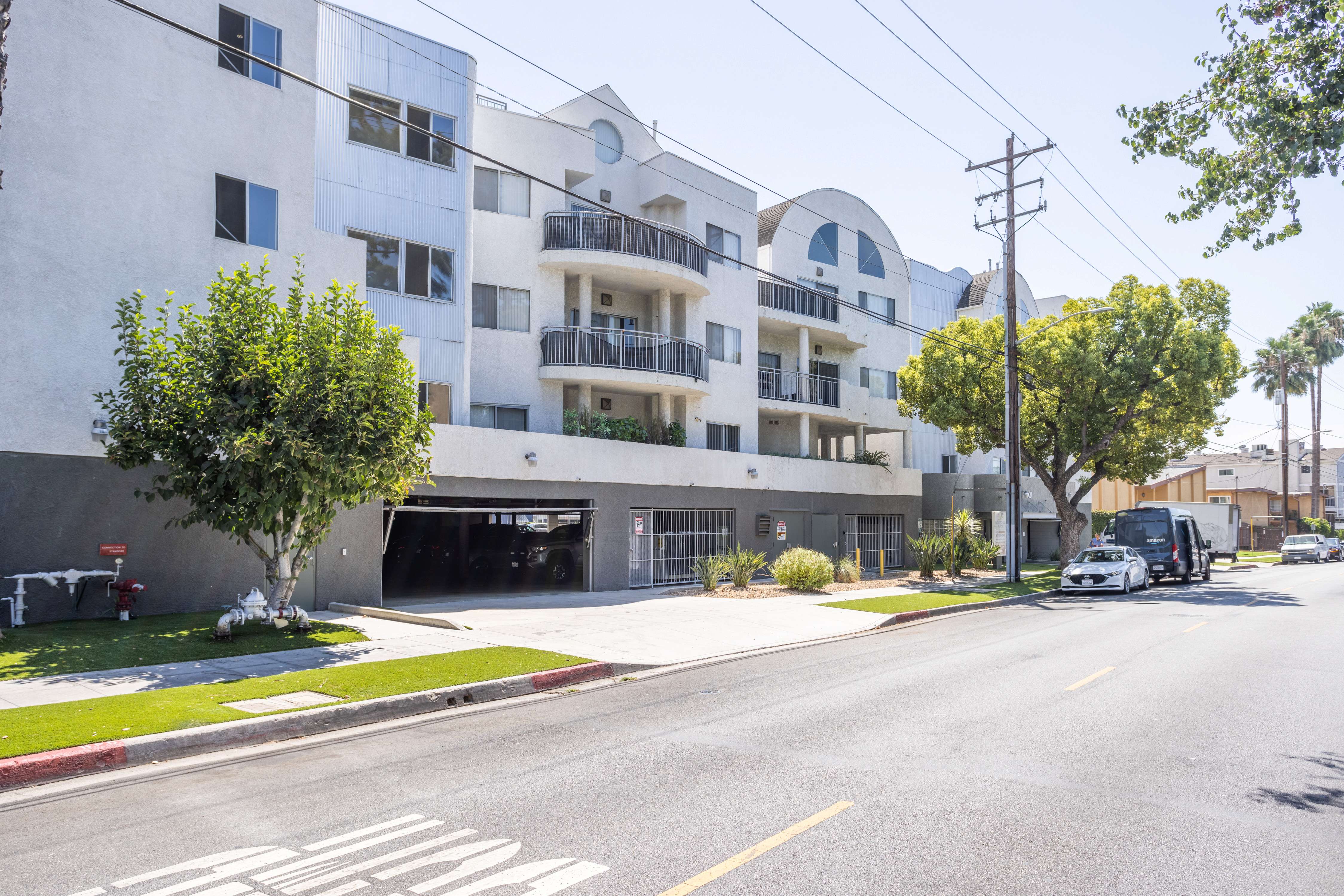 A street view of a white apartment building with a black garage door.