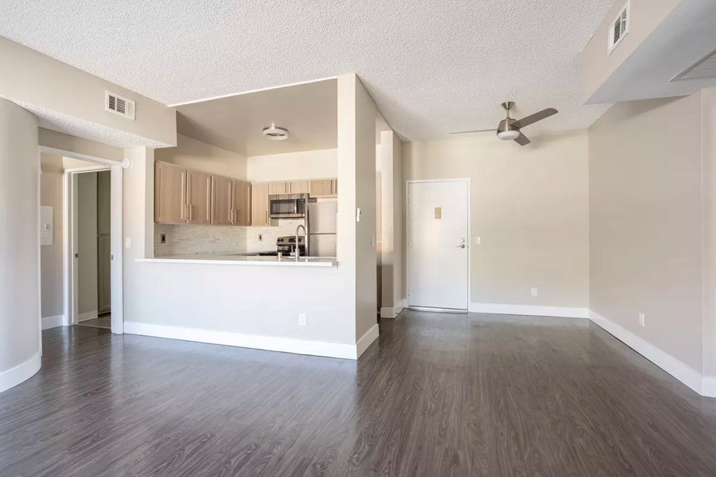 an empty living room and kitchen with a ceiling fan