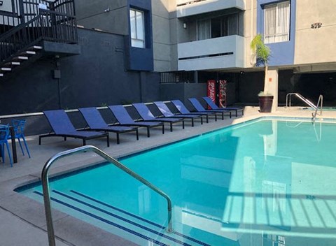 a swimming pool with blue chairs next to a building