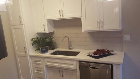 a small kitchen with white cabinets and a sink