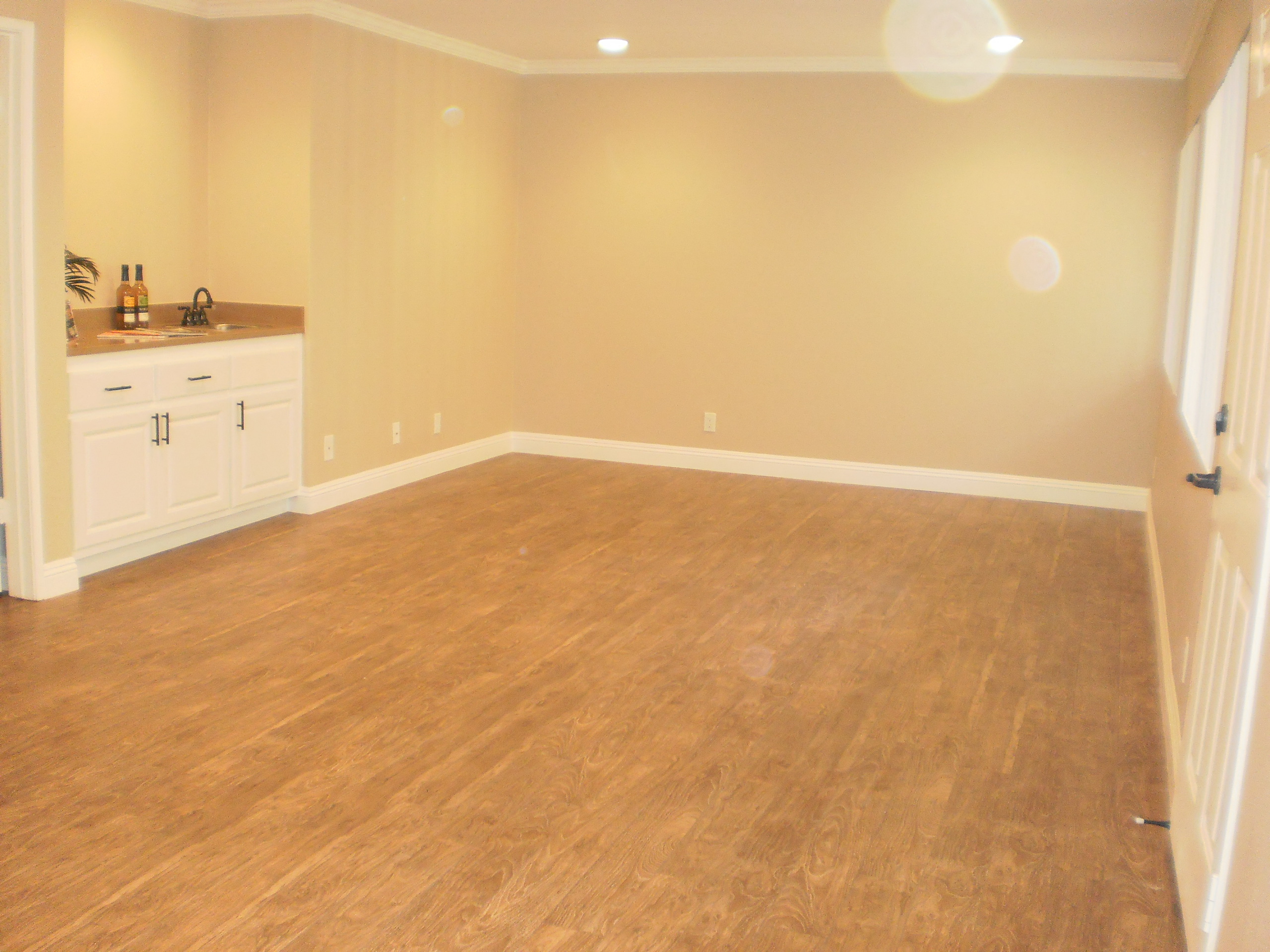 an empty living room with a wooden floor and white cabinets