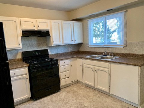 a kitchen with white cabinets and a black stove and a sink
