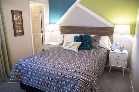 a bedroom with a bed with pillows and a night stand