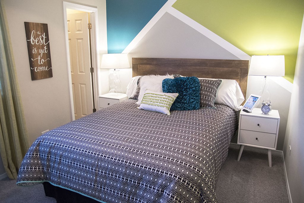 a bedroom with a bed with pillows and a night stand