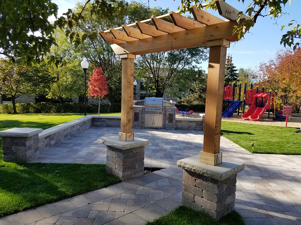 a paver patio with a pergola in a park