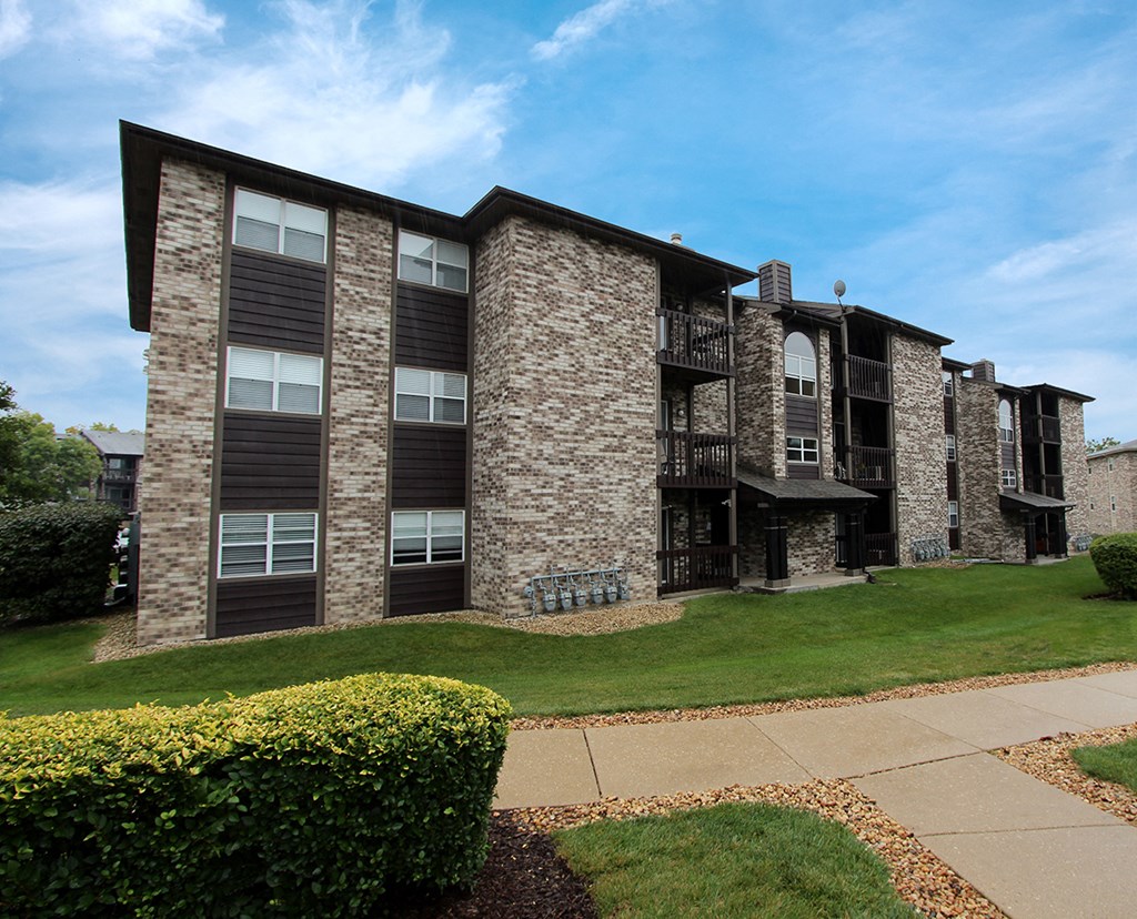 an apartment building with a lawn and a sidewalk