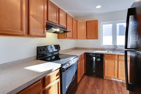an empty kitchen with wooden cabinets and black appliances