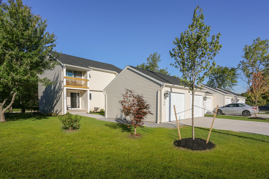 the exterior of a white house with a yard and a tree