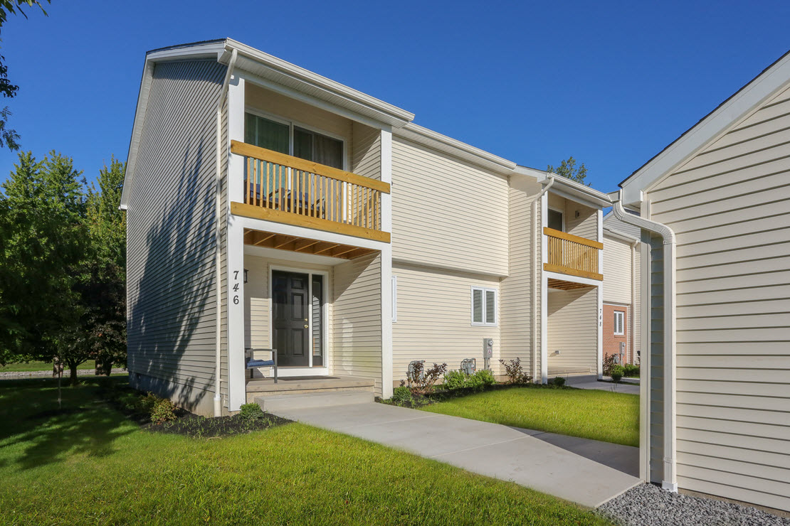 the front of a white house with a yard and a balcony