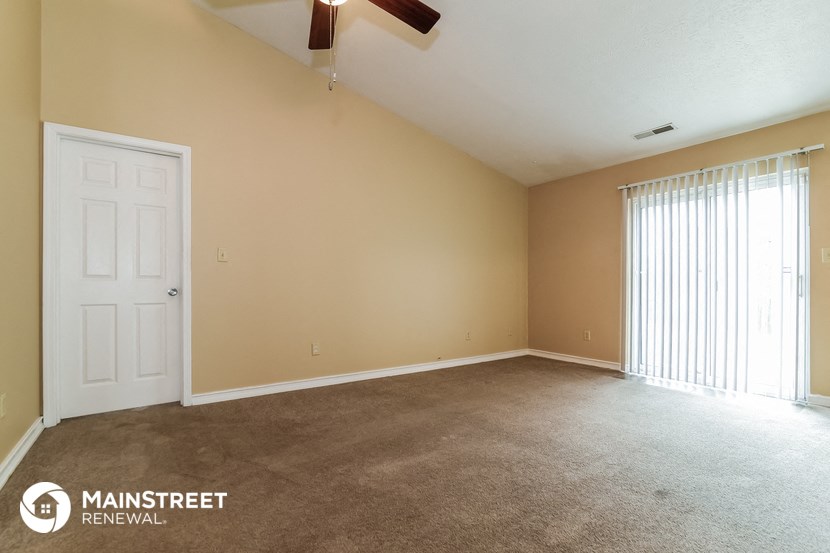 the living room of an apartment with carpet and a white door