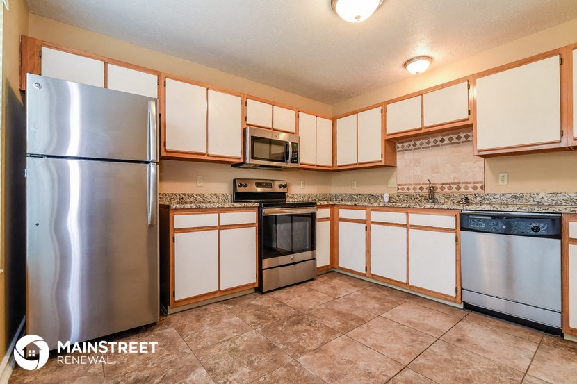 the kitchen has stainless steel appliances and white cabinets