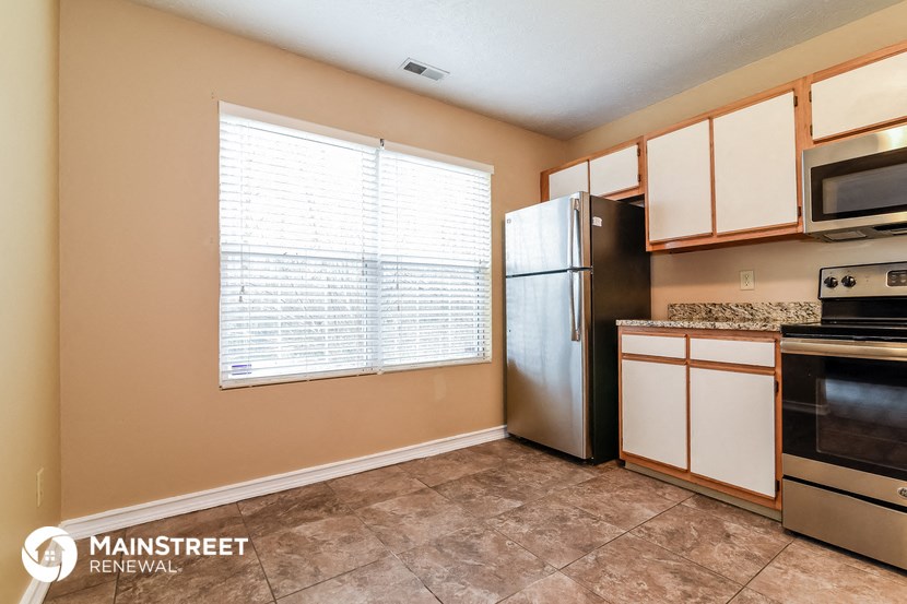 a kitchen with a refrigerator and a stove and a window