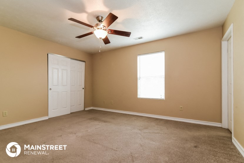 the living room of this home has a carpeted floor and a ceiling fan