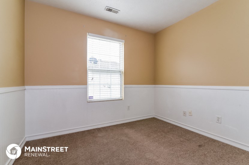 the living room of a home with white walls and a window