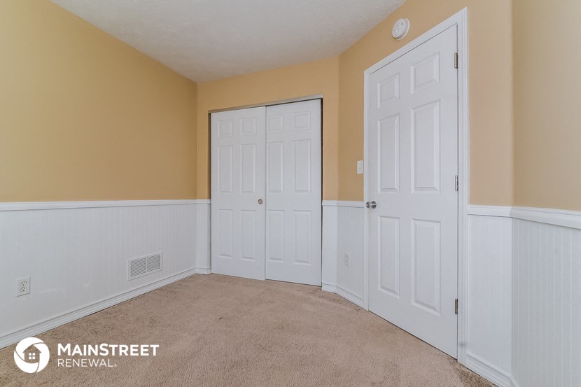 a bedroom with two white doors and a carpeted floor