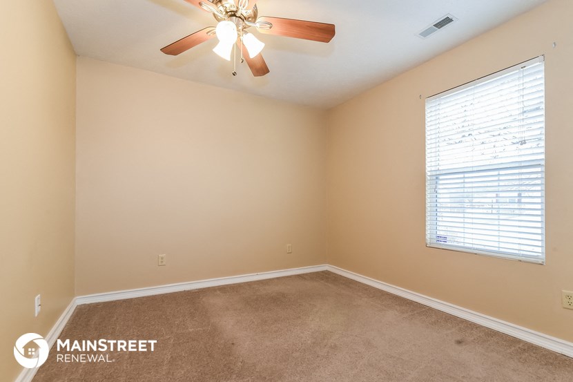 the spacious living room with ceiling fan and large window