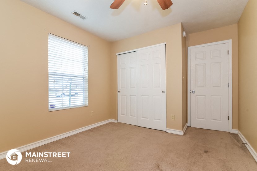 a bedroom with two doors and a window and a ceiling fan