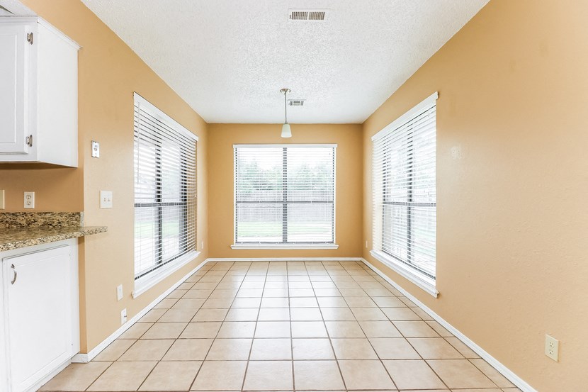 an empty living room with a large window and a tiled floor