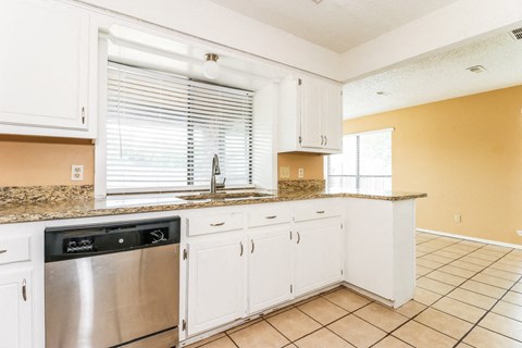 a kitchen with white cabinets and a stainless steel dishwasher