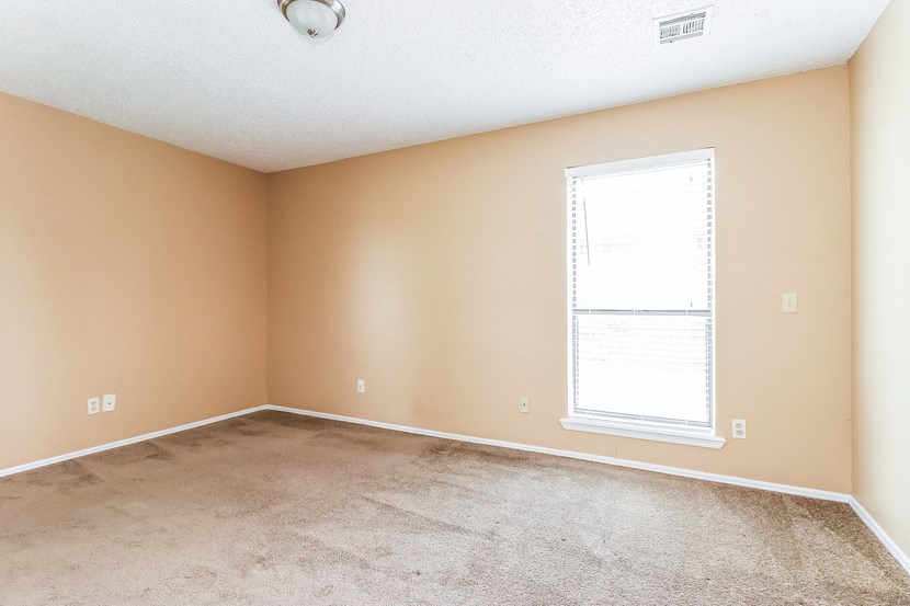 an empty living room with a window and carpet