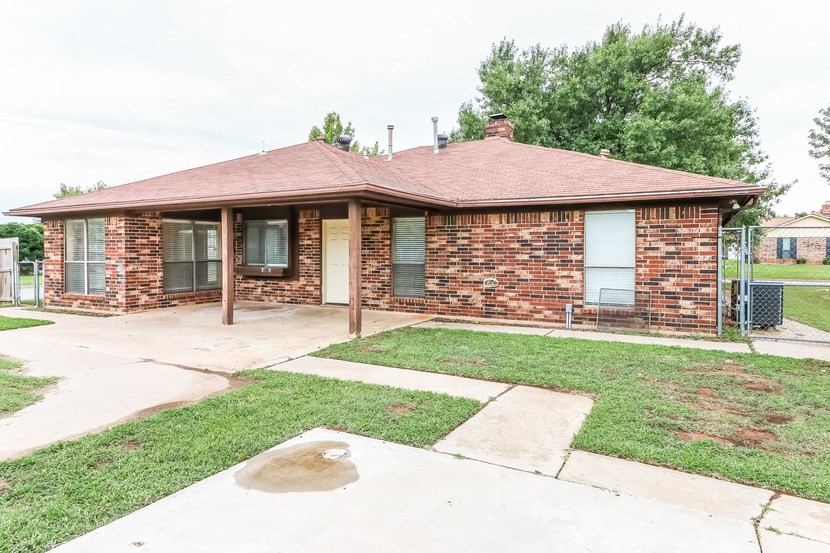 a small brick house with a yard and a sidewalk