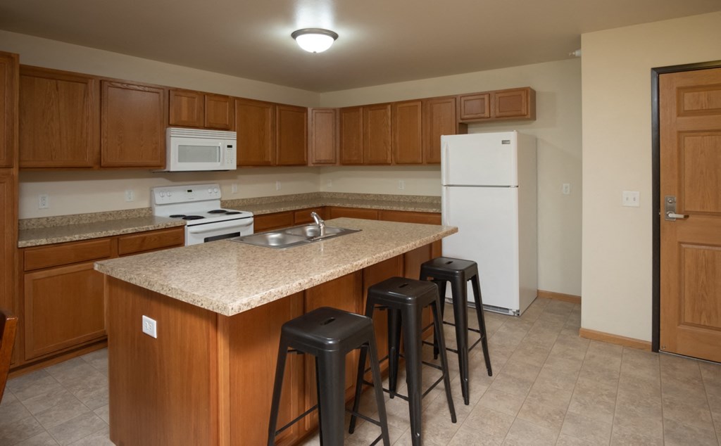 a kitchen with an island with bar stools and a refrigerator