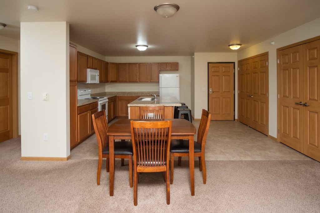 a dining room and kitchen with a wooden table and chairs