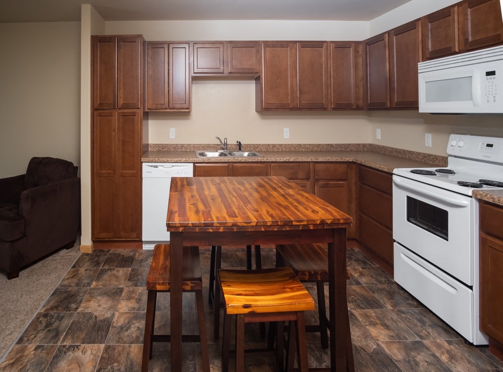 a kitchen with white appliances and a wooden table